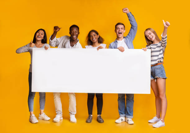 Happy smiling group of students standing together with white placard
