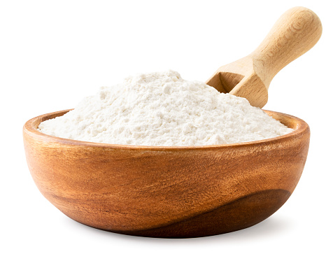 Flour in a wooden plate with a scoop close-up on a white background. Isolated