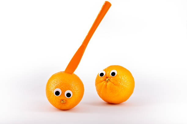 istock Two oranges with wiggly eyes, one murdered by a knife. Funny pic 1199683560