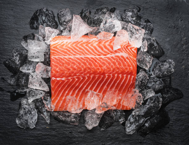 istock Fresh salmon fillet over ice on black cutting board. 1199684927