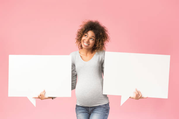 istock African-american pregnant lady holding two blank speech bubbles 1199685002