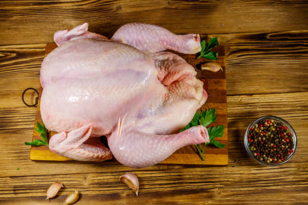 istock Raw whole chicken with spices on a wooden table. Top view 1199686235