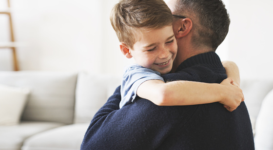Shot of a little boy hugging his father at home