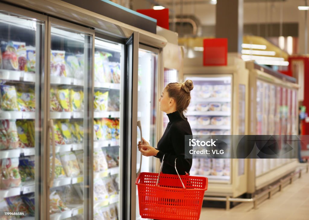 Woman choosing frozen food from a supermarket freezer Supermarket Stock Photo