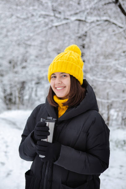istock smiling woman in winter outfit drinking warm up drink from refillable mug 1199687385