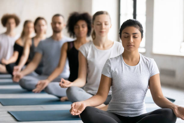 istock Beautiful Indian woman meditating at group lesson, practicing yoga 1199687512