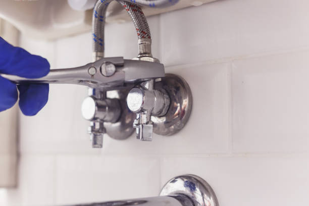 istock Plumber turns nut on angle valve under wash basin using spreading wrench. 1199687878