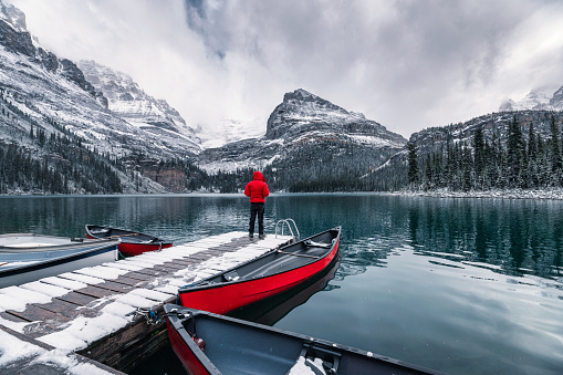 Man traveler standing on wooden pier with rocky mountains in Lake O'hara at Yoho national park, Canada