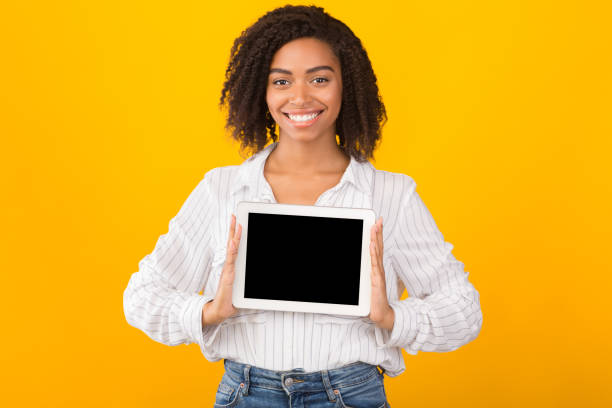 istock Smiling black woman showing blank computer screen 1199692353