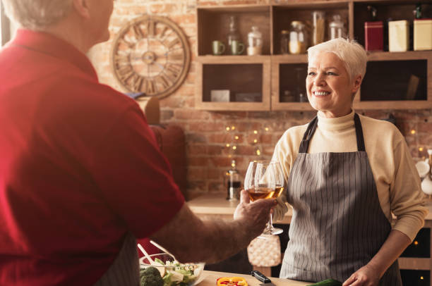 istock Aged couple in love clinking with wine glasses at kitchen 1199692551