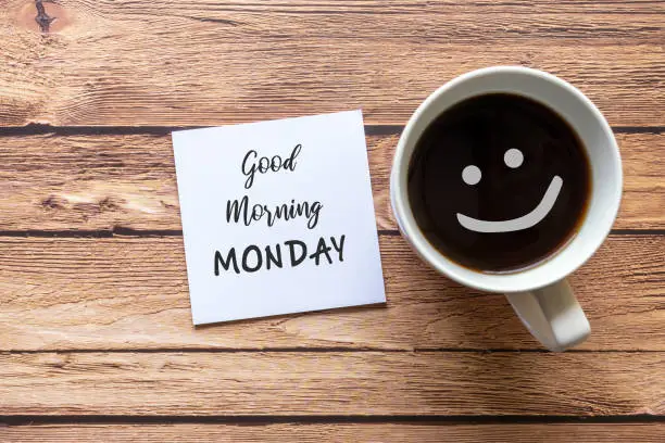 Good Morning Monday greeting on paper note with cup of coffee