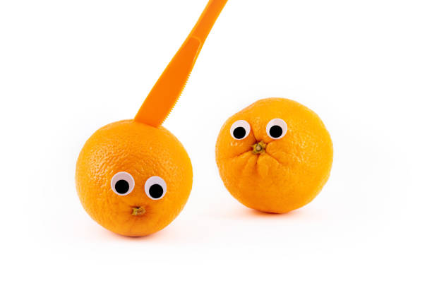 istock Two oranges with wiggly eyes, one murdered by a knife. Funny pic 1199692953