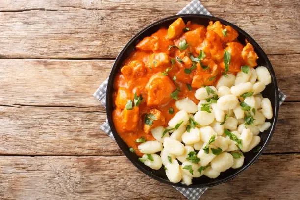 Photo of Hungarian Chicken Paprikash features tender braised chicken and a tangy sauce spiced with paprika closeup on a plate. Horizontal top view