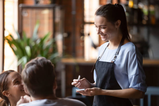 lächelnde weibliche kellnerin nehmen bestellung sprechen mit kunden paar - waitress stock-fotos und bilder