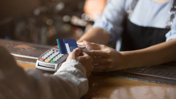 client féminin retenant la carte de crédit près de la technologie de nfc sur le compteur - cash box photos et images de collection