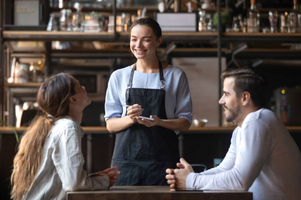 istock Smiling waitress hold notepad take order serving couple customers 1199696859