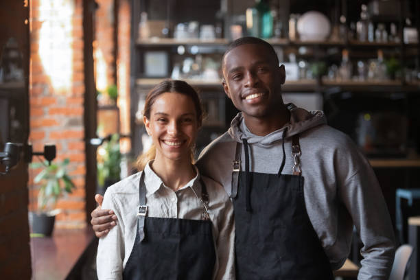 istock Happy diverse waiter and waitress looking at camera in restaurant 1199696871