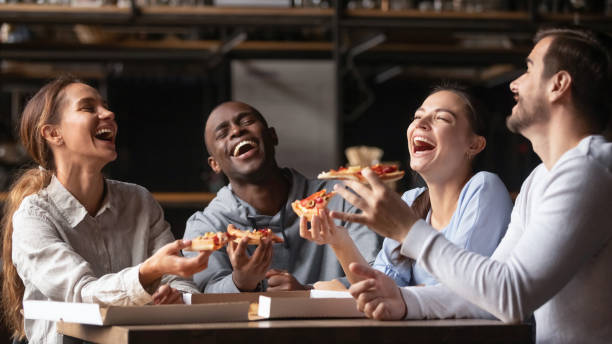 istock Happy diverse friends laughing at funny joke share pizza 1199696881
