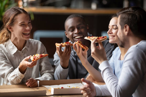 wesoły wielorasowy szczęśliwy przyjaciele śmiać się dzielić pizza w kawiarni razem - pizza pizzeria friendship people zdjęcia i obrazy z banku zdjęć