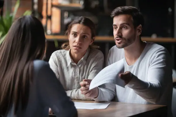 Photo of Angry couple arguing with bank manager complain on bad contract