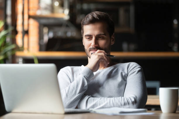 Thoughtful businessman think of online project looking at laptop Thoughtful businessman think of online project looking at laptop at workplace, dreamy professional consider solution sit at work desk with computer, student search new idea inspiration in office cafe skeptical look stock pictures, royalty-free photos & images