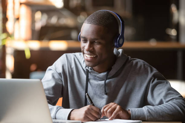 웃는 아프리카 젊은 남자 학생 착용 헤드폰 공부 온라인 - cyberspace support computer assistance 뉴스 사진 이미지