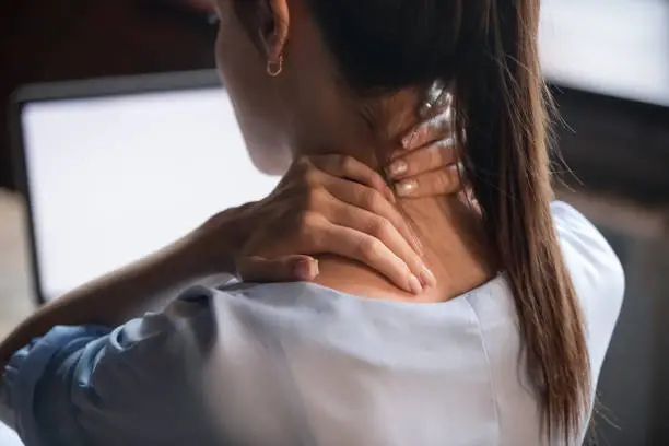 Photo of Tired woman rubbing stiff sore neck, close up rear view