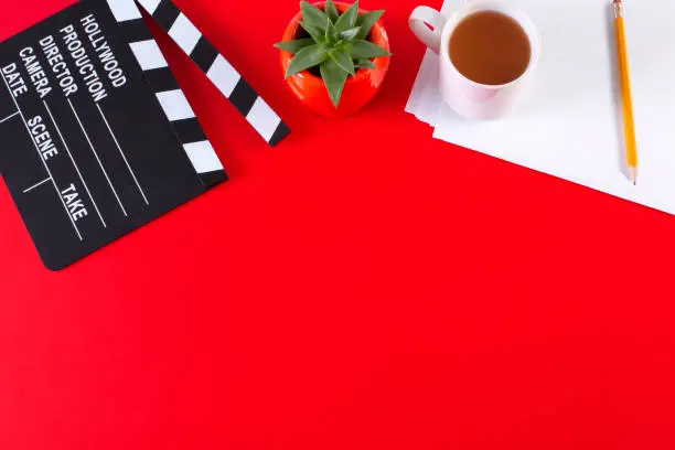 Photo of Movie clapper board and coffee cup on red background with copy space