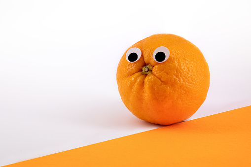 Fresh orange with wiggly eyes on orange background