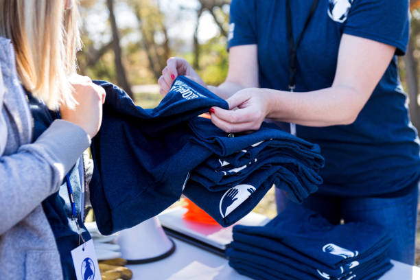 istock Close up photo women's hands setting up t-shirts for event 1199705879