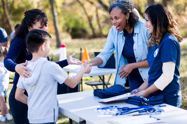istock Boy shakes hands with volunteer at park cleanup registration table 1199706210