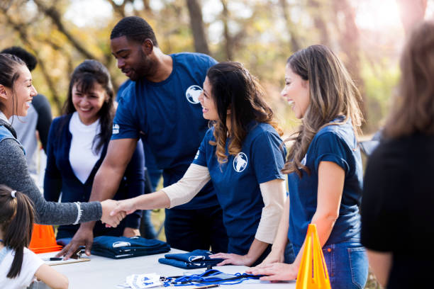 istock Women shake hands across event registration table 1199706231