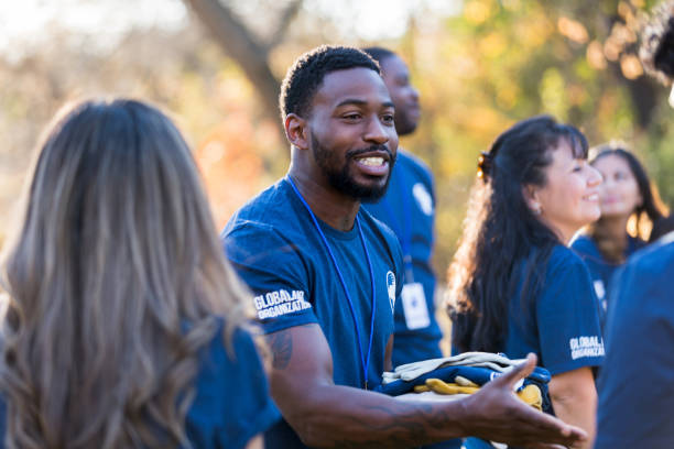 Charity event organizer greets volunteer during community cleanup event