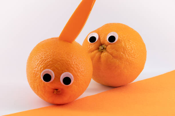 istock Two oranges with wiggly eyes, one murdered by a knife. Funny pic 1199709348