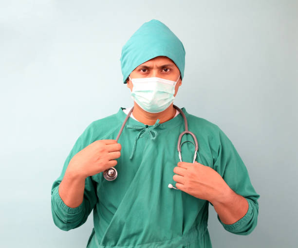 chirurgo asiatico maschio, chirurgo che mostra stetoscopio con maschera da chirurgo, su sfondo blu in studio. - surgeon isolated paramedic operating room foto e immagini stock