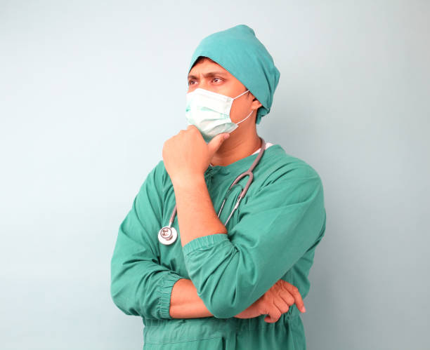 chirurgo asiatico maschio, chirurgo che mostra stetoscopio con maschera da chirurgo, su sfondo blu in studio. - surgeon isolated paramedic operating room foto e immagini stock