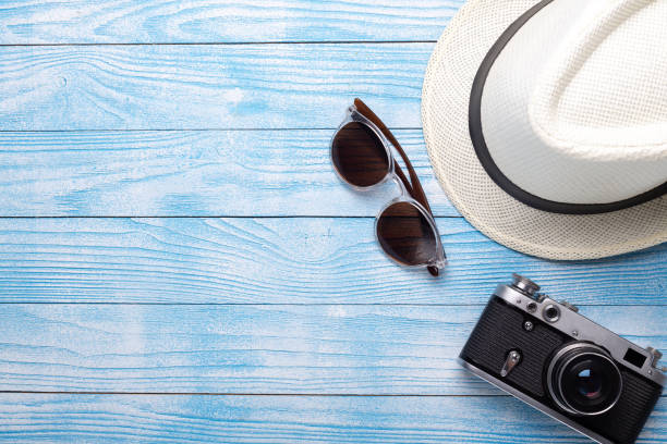 Summer flat lay. Straw hat, retro camera and sunglasses on blue wooden background, top view. Holiday concept stock photo