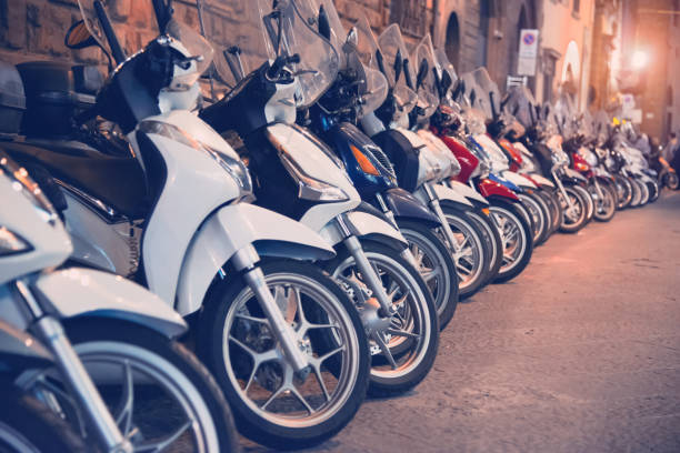 scooters de stationnement dans une rangée par nuit - parking vélo photos et images de collection