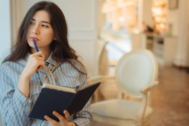 istock Thoughtful young woman holding notepad and thinking on creative ideas for writing essay in a cafe 1199715346