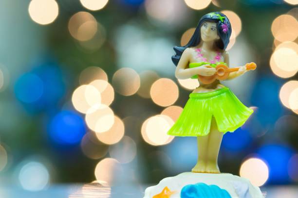 Hula Girl doll playing the ukulele with bokeh lights.