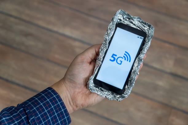 5g network danger concept. Smartphone with protective case made out of aluminum foil to block the signal. Danger sign is displayed on the phone.