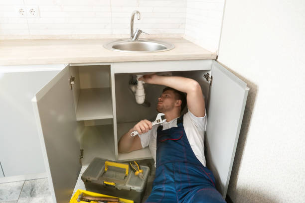 istock young man plumber in uniform fixing the sink with adjustable spanner in his hand lying on the kitchen floor professional plumbing repair service 1199720257