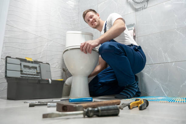 smiling man plumber in uniform repairing toilet bowl using instrument kit looks happy professional repair service smiling man plumber in uniform repairing toilet bowl using instrument kit looks happy professional repair service. toilet photos stock pictures, royalty-free photos & images