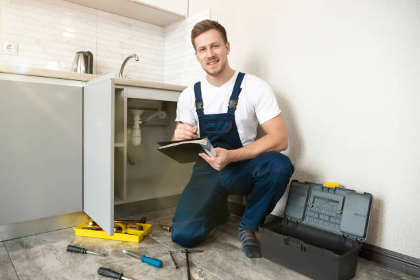 istock young handsome man plumber looks happy while taking notes in checklist during pipe fixing work in the kitchen professional plumbing repair service 1199720294