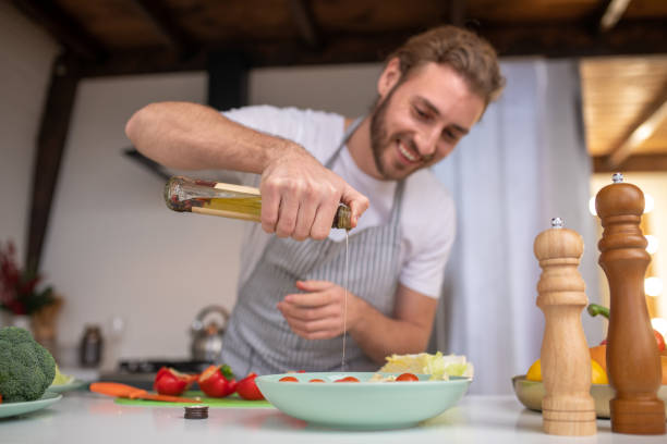 istock Concentrated cook putting some oil into a salad 1199720694