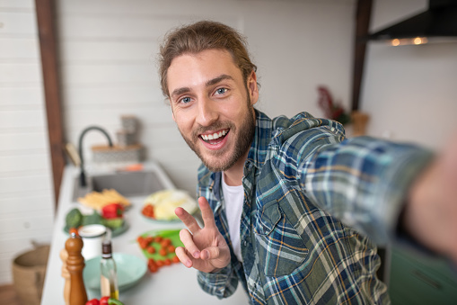 Boasting with a new meal. A smiling man making selfie on his kitchen