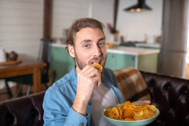 istock Joyful amn eating tasty chips at home 1199720994