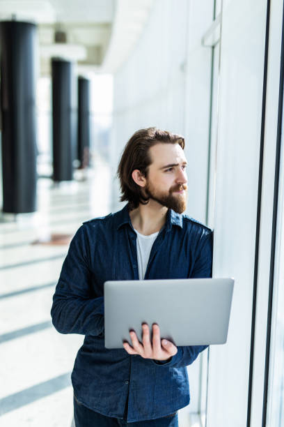 istock Business man using laptop with panoramic city view outside window background 1199723358