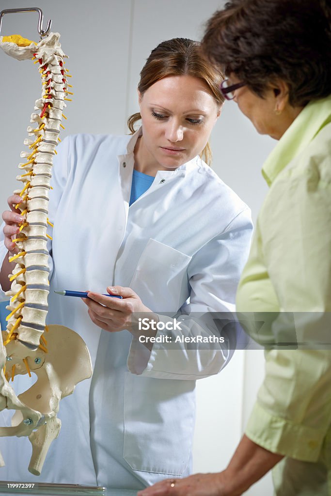 chiropractic Physical Therapist shows the problem areas on the model of the spine to patient and  explains the cause of her pain. Physical Therapy Stock Photo