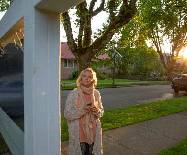 mulher madura olha para placa imobiliária em rua residencial - adventure business horizontal real estate - fotografias e filmes do acervo